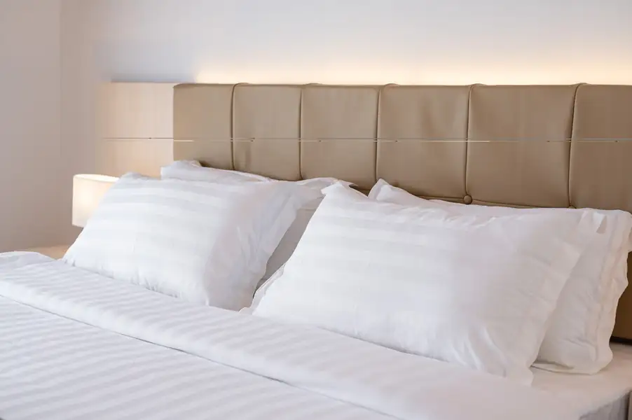 King bed with swan towel art facing glass doors opening onto the balcony at Sand Bay Resort