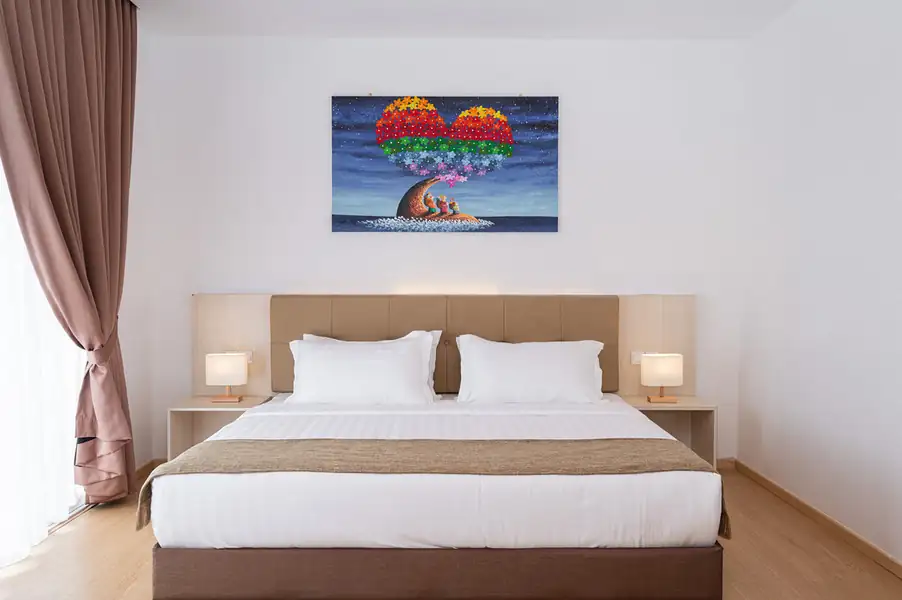 Bedroom with large bed and colourful wall art with wooden plank floor at Sand Bay Resort