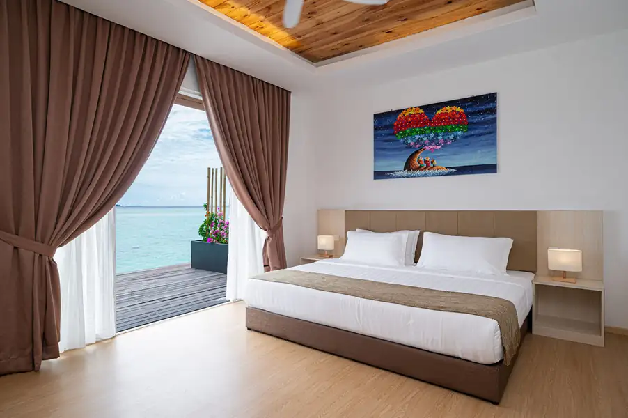 Bedroom with large bed beside glass doors opening onto the balcony at Sand Bay Resort