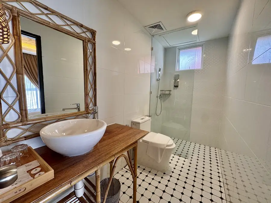 Contemporary bathroom with dark grey stone-style wall tiles and wooden vanity at Sand Bay Resort