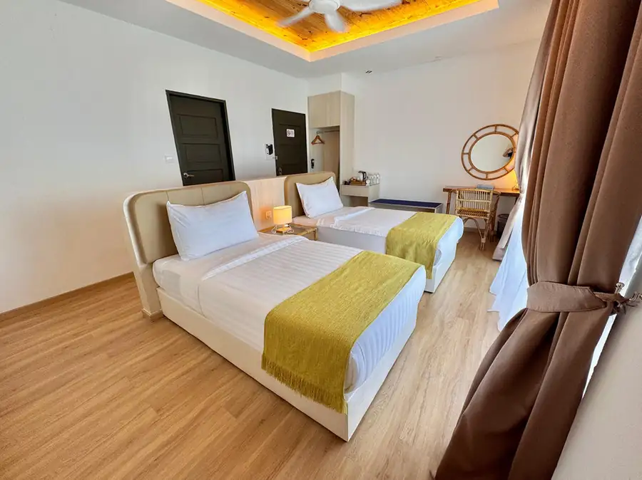 Stylish bedroom with two single beds and vanity desk with polished teak wood floors at Sand Bay Resort