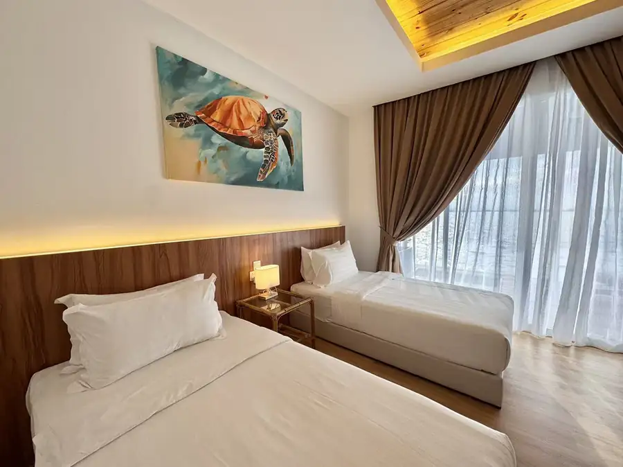 Comfortable bedroom with two beds beside floor-to-ceiling glass doors at Sand Bay Resort