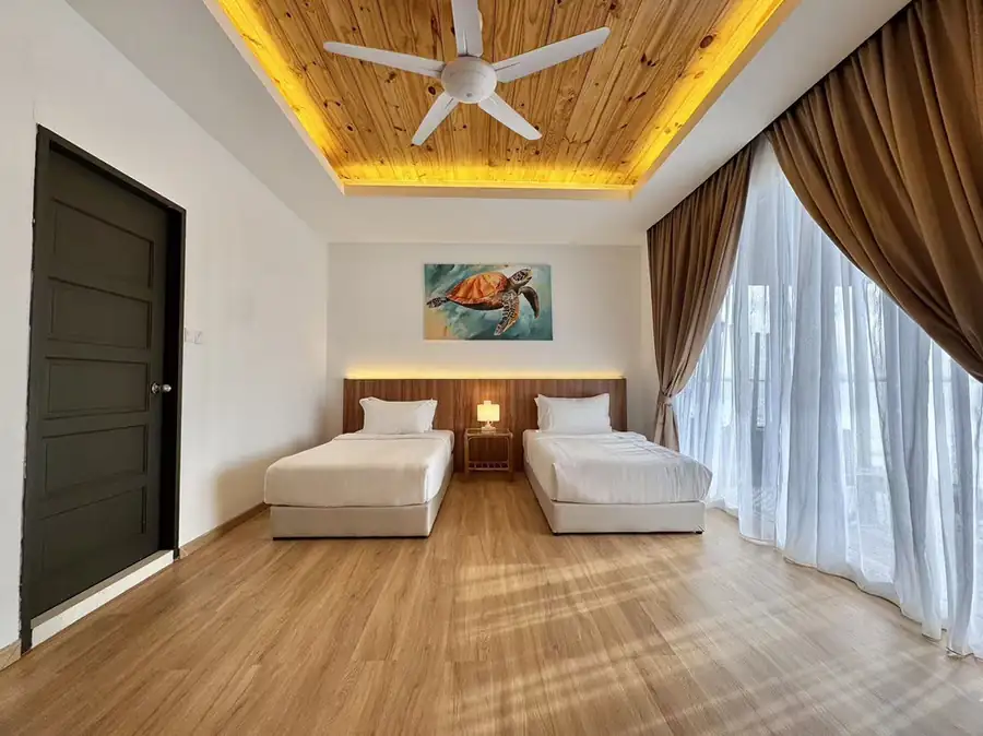 Twin beds under turtle wall art and panoramic glass doors at Sand Bay Resort