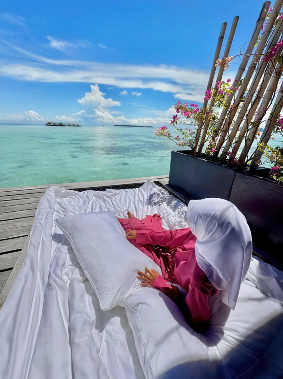 Guest relaxing on a floor mattress on a private sunlit balcony at Sand Bay Resort