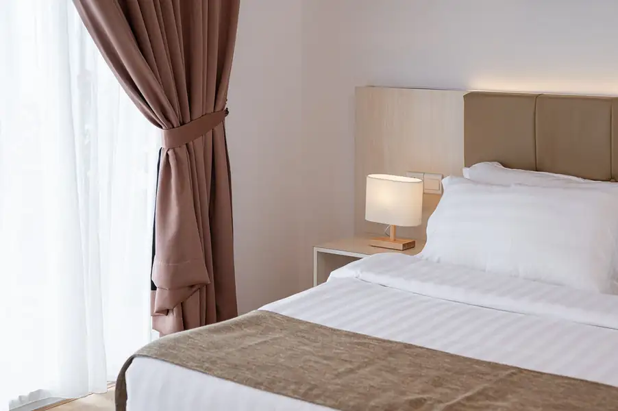 Plush bed with pink decorative runner and warm bedside lamp at Sand Bay Resort