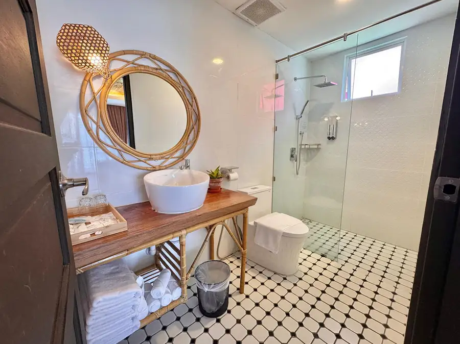 Family bathroom with long wooden vanity, backlit mirror and glass-enclosed shower at Sand Bay Resort