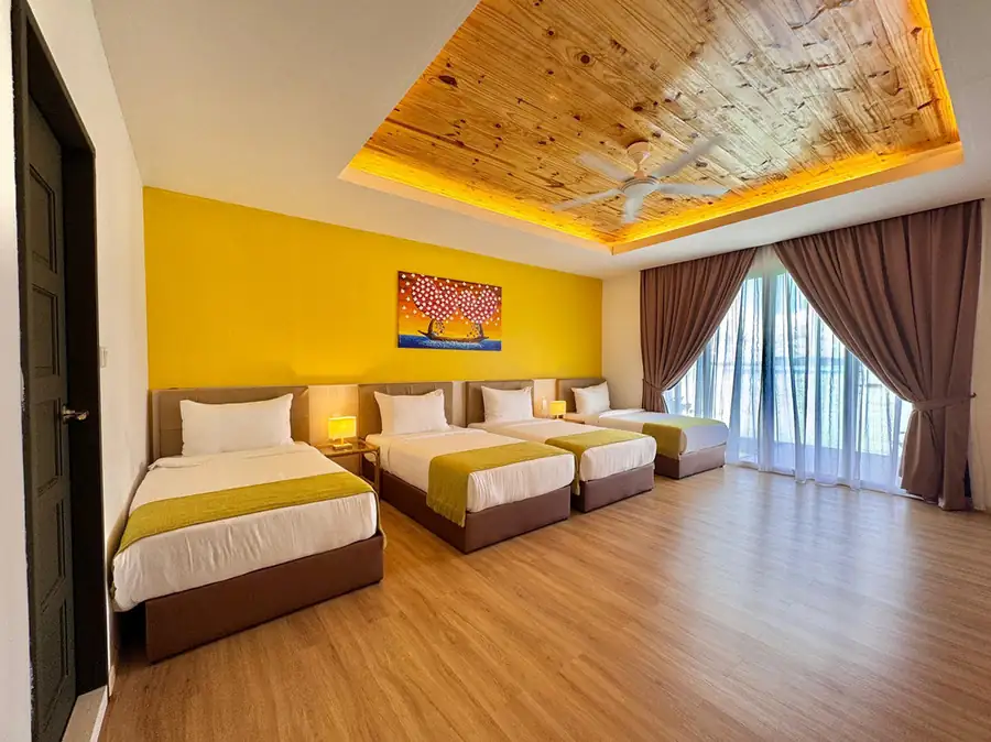 Family bedroom with four single beds against a yellow wall and balcony access at Sand Bay Resort