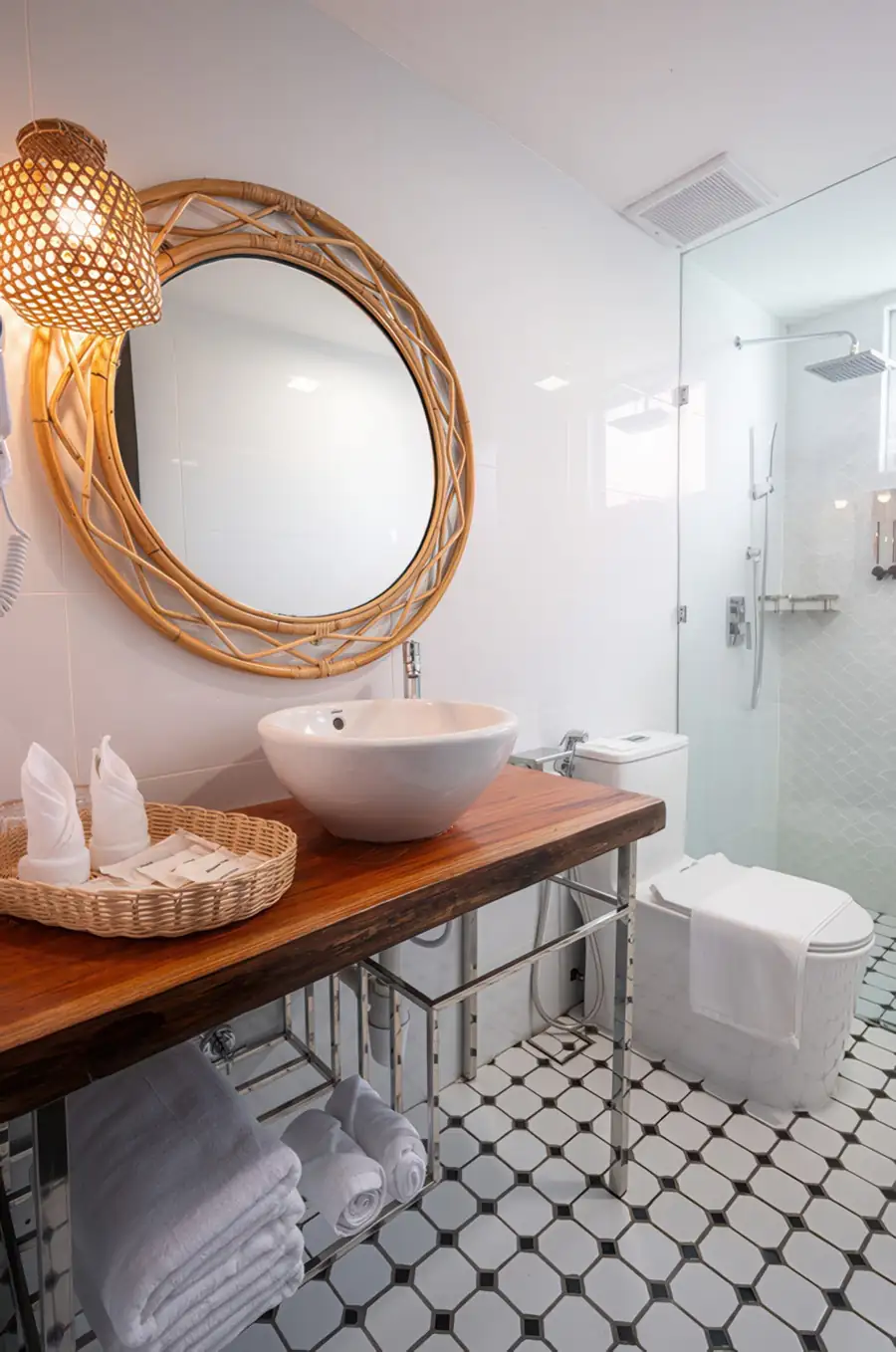 Modern bathroom vanity with backlit round mirror and dark wall tiles at Sand Bay Resort