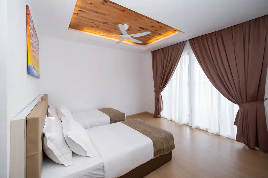 Twin bedroom with two single beds facing floor-to-ceiling glass doors at Sand Bay Resort