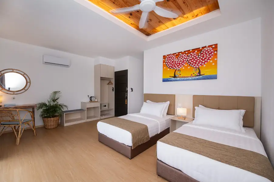 Twin bedroom with two single beds, wooden desk and wall art at Sand Bay Resort